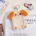 Close-up of cute beige plush dog photo card holder with metal keychain on tray - Brown Ear Dog
