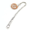 Macro view of silver bookmark with engraved celestial patterns and orange bead swirl - Silver + Light Pink