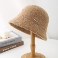 Close-up of curly boucle fabric texture and wavy silver metal badge on camel bucket hat - Khaki