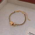 Dettaglio del bracciale intrecciato dorato con ciondolo a cilindro e fiori in zircone - Bracciale - Oro (Grande)