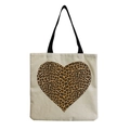 Detail of beige canvas tote bag featuring a bold leopard print heart pattern and black straps - Heart-shaped Leopard Print (hm2696)
