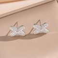 Silver criss-cross stud earrings with pavé crystals on soft beige fabric background - Silver X-Shape Stud Earrings