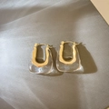 Detailed view of U-shaped gold metal and clear resin earrings in a modern geometric style - Clear