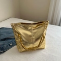 Golden large capacity tote bag in glossy finish with gold chain strap on bedding - Gold