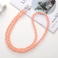 Nahaufnahme der zweireihigen perlenbesetzten Umhängekette mit silbernen Metallschnallen - Kürbis Perle Crossbody Kette / Orange