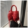 Detail shot of a red PU leather handbag with a large bow decoration and smooth finish - Red