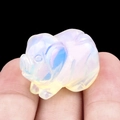 Miniature opal pig crystal carving held in fingers showing its translucent glow - Opal (Synthetic)
