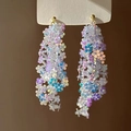Close-up of iridescent flower sequin tassel earrings with elegant golden metal hooks - Silver Needle / Blue, White