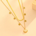 Detalle de collar dorado de doble capa con colgantes de concha y cadena de serpiente - Collar De Doble Capa Con Concha Festoneada Dorada (H813)