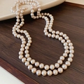 Elegant beaded necklace with cream pearls displayed on a dark wood texture surface - Champagne