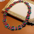 Dettaglio di una collana vintage in oro con smalto verde e perle rosse su pelle - Collana-Oro-Verde