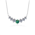 Macro shot of V-shaped S925 silver pendant with green center stone and white side stones - Teal