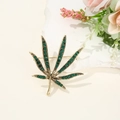Vintage-Brosche aus Bronze in Hanfblatt-Form mit grünen Kristallen auf weißem Stein - Antik Bronze Cannabis Blatt Stil