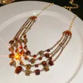 Collana vintage a strati dorata con pietre ambrate e nappe a triangolo su piatto ceramico - Collana Girocollo Multistrato / Marrone oro
