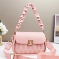 Detailed view of pink crossbody bag with litchi grain texture and gold square buckle - Pink