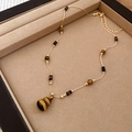 Macro detail of Tiger Eye gourd pendant necklace on a beige velvet jewelry tray - Gourd Pendant Clavicle Chain / Gold Brown