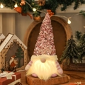 Gnomo navideño de lentejuelas rosas con luz LED cálida y brazos a rayas sobre madera - Rosa