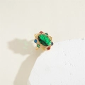 Primer plano de un anillo cóctel vintage dorado con gema verde y detalles de colores - Abierto Ajustable / Verde Esmeralda Ovalado