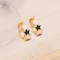 Close-up of gold star earrings with black and white enamel finish on a clean background - Black and White