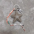 Detail van een stervormige lederen sleutelhanger met stiksels en stoffen band met motief - Khaki