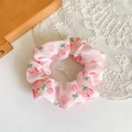 Detailed close-up of a pink fabric hair scrunchie with red cherry patterns on white lace - Pink Cherry Large