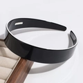 Close-up of a wide black non-slip headband with glossy finish on a display tray - Wide Version / Black