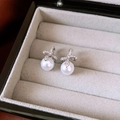 Dettaglio di orecchini a fiocco d'argento con zirconi e eleganti perle bianche tonde - Argento (Perno in argento)