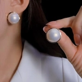 Close-up of large white pearl earrings with elegant gold metal trim on model - High-light Pearl (Creamy White)