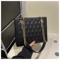 Detailed close-up of diamond quilted texture and gold chain on black tote bag - Black