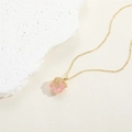 Detailed shot of pink heart zircon pendant with golden coral accents on a sandy background - Crushed Stone Wrapped Pendant / Pink 14K Gold