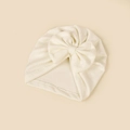 Detail showing the white knitted texture and large handmade bow of the infant turban hat - 18.5x17cm / Off White