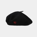 Close-up of a black wool beret featuring a small red heart embroidery on the side - Black