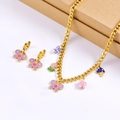 Detail of gold chain necklace set with purple butterfly, floral, and porcelain charms - Necklace + Earrings