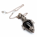 Macro view of gothic bronze pendulum necklace with black gemstone and star engraving - Obsidian + Pendulum Chain