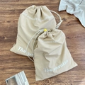 Detail of canvas drawstring bags with adjustable yellow toggles on a wooden floor - Small (30x37cm) / Brown