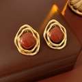 Macro detail of vintage gold rhombic earrings with red square gemstone on leather box - Silver Needle / Brown