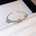 Golden open bangle featuring pink and purple zircon gemstones in a refined bow design - Style 26 / Gold