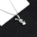 Détail de collier chaîne box argenté avec pendentif lapin 3D sur un plateau en pierre - Lapin Souriant de Dessin Animé