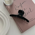 Detail of glossy black acetate hair claw with gold France Handmade logo on a book - Black