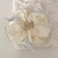 Close-up of cream-colored scrunchie with blue ribbon bows and delicate wavy edge detail - Blue Bow