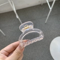 Hand holding a transparent pink butterfly hair claw clip with golden metal spring detail - Transparent Champagne