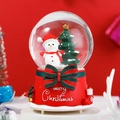 Close-up of Christmas snow globe featuring a snowman and tree on a red festive base - 80 Medium Music+Light / Tree Snowman