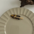 Close-up of a large leopard print hair claw clip on a ceramic plate with wooden decor - No-Crease Hair Clips