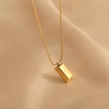 Gold rectangular bar pendant necklace with sleek snake chain on silk background - Small Gold Brick Necklace