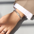 Detalle de una pulsera de cadena cubana minimalista de acero titanio en la muñeca - Pulsera / Chapado en oro 18K / Plateado