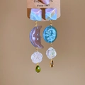 Nahaufnahme asymmetrischer Sonnen- und Mond-Ohrhänger aus Harz mit matten Blumen - Asymmetrische Sonne & Mond (Silberstift - Blau - Violett)