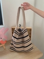 Detail einer beige-schwarz gestreiften Stricktasche mit Webstruktur und langem Riemen - Khaki