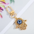 Detail of gold Hamsa hand keychain with blue evil eye and sparkling crystals - Gold Hollow Flower Hand 12