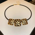 Dettaglio di pendenti rettangolari leopardati su cordoncino nero con cristalli ambrati - Collana d'Oro (Quadrato Leopardato)