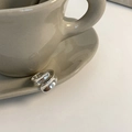 Anello largo in argento sovrapposto su un piatto di ceramica beige, stile elegante - Anello Aperto Largo Sovrapposto Argento (J3911)
